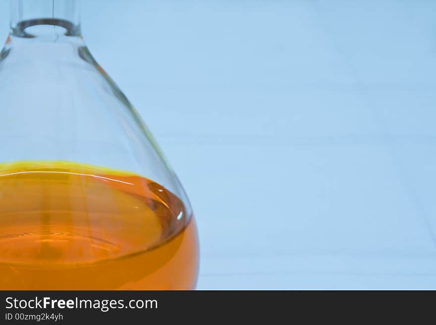 Detail image of a lab flask containing an orange solution (soft focus). Detail image of a lab flask containing an orange solution (soft focus)