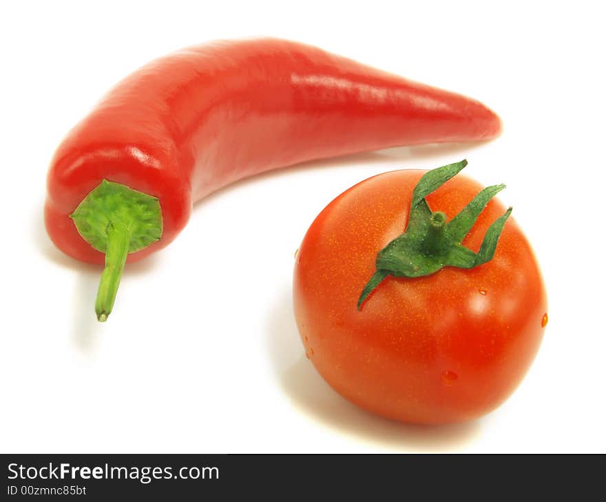 A fresh tomato and a ripe chili pepper isolated on white background. A fresh tomato and a ripe chili pepper isolated on white background