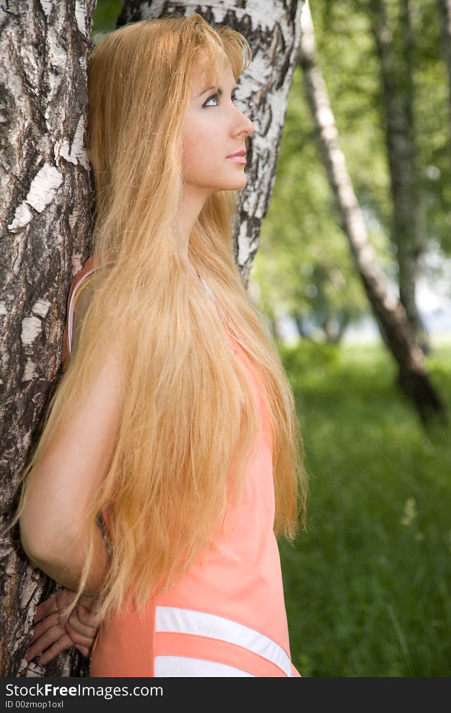 Young woman leaning against birch in forest