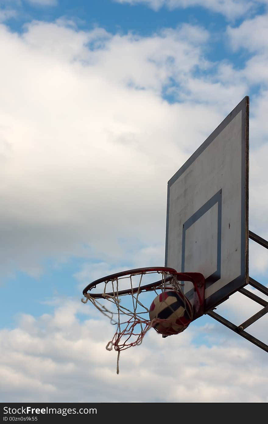 Striped ball inside the hoop against the cloudy sky. Striped ball inside the hoop against the cloudy sky