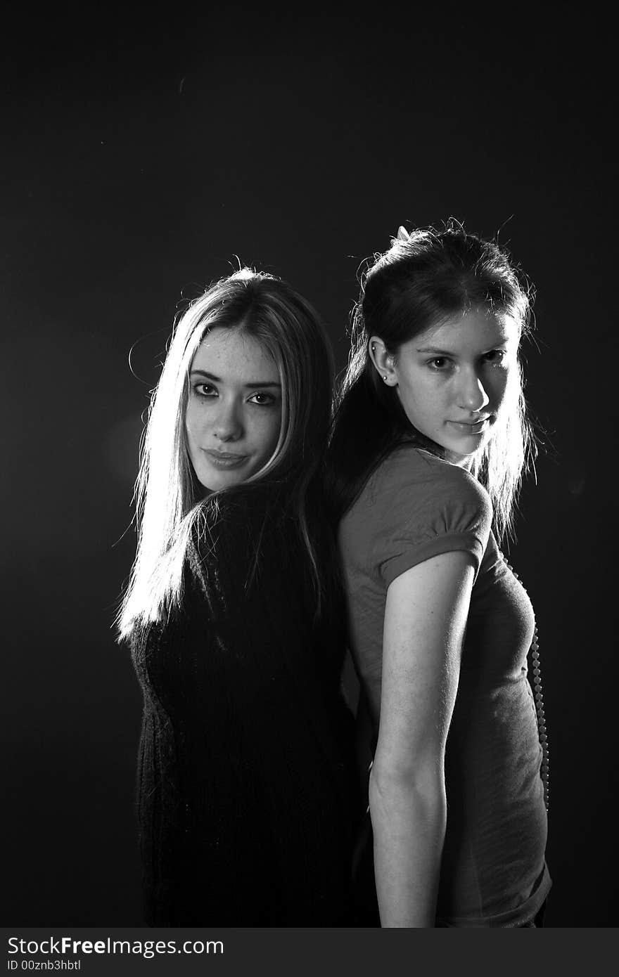 Two teenage girls standing back to, in black and white. Two teenage girls standing back to, in black and white