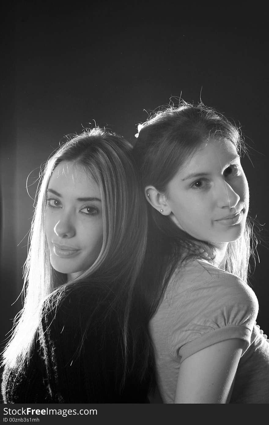 Black and white portrait of 2 sisters standing back to back. Black and white portrait of 2 sisters standing back to back