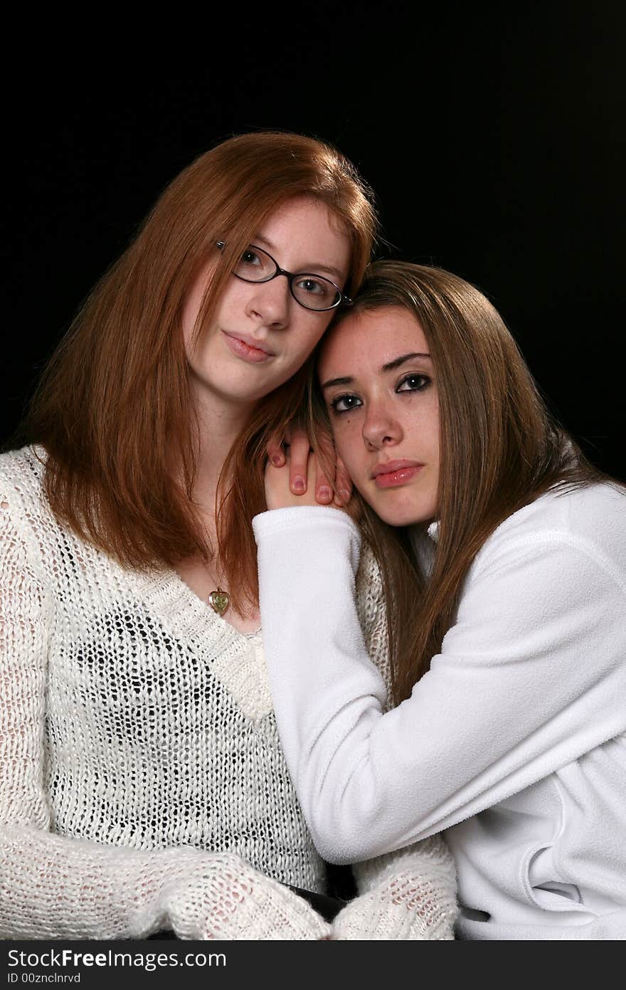 Two sisters in white sweaters, sitting together with their heads touching. Two sisters in white sweaters, sitting together with their heads touching.