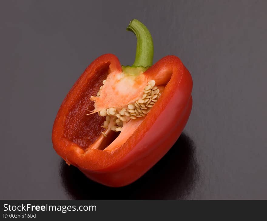 A red pepper cut in half on a black background. A red pepper cut in half on a black background.