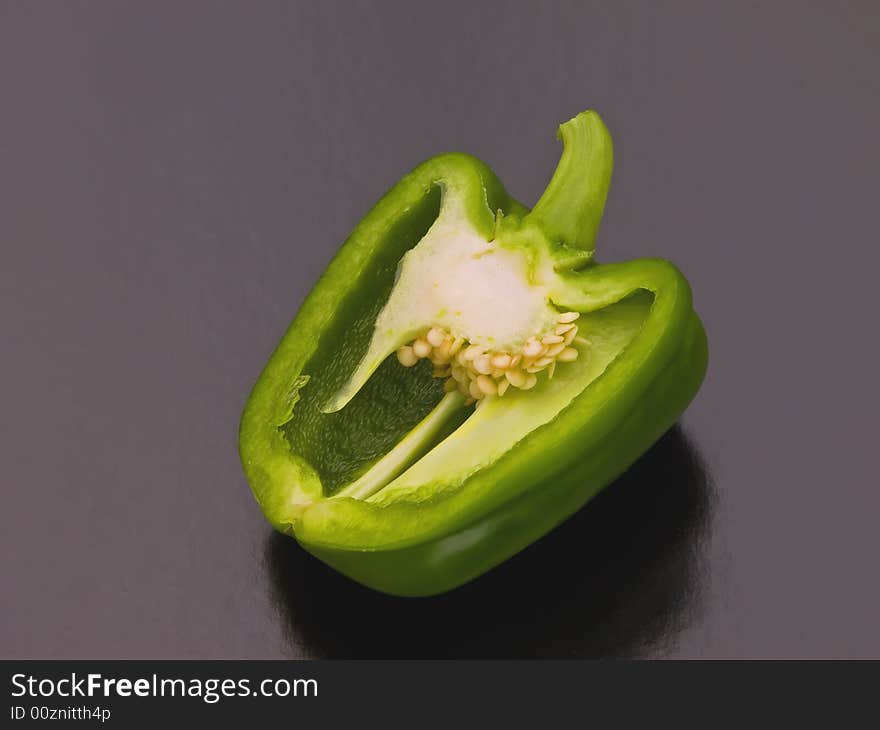 A green pepper cut in half on a black background. A green pepper cut in half on a black background.