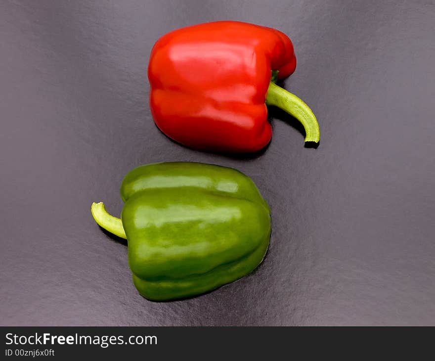 A red and a green pepper cut in two and laid face down to give a pattern on a black background. A red and a green pepper cut in two and laid face down to give a pattern on a black background.