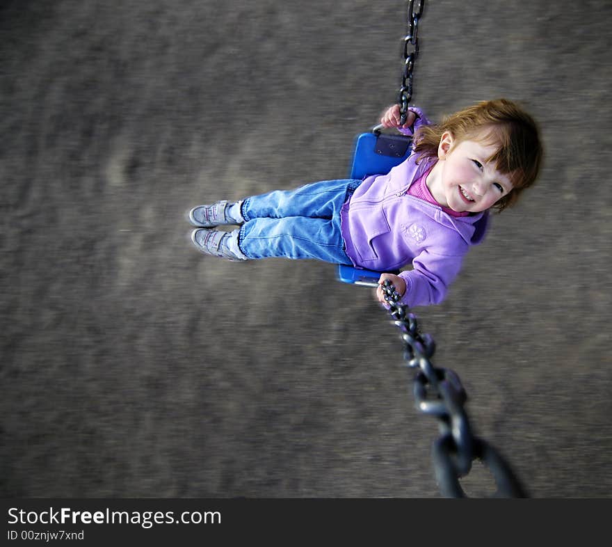 Little girl playing on merri-go-round at a park. Little girl playing on merri-go-round at a park