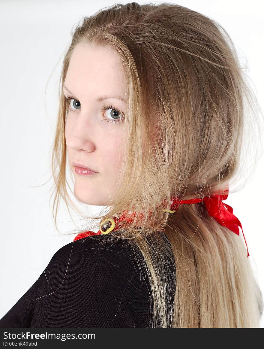 Girl with long blond hair with red ribbon wearing black dress looks backward. Girl with long blond hair with red ribbon wearing black dress looks backward