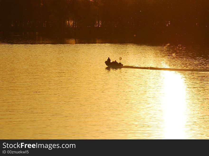 A powerboat heads home after a day of fishing.  As they travel their wake breaks the reflection of the setting sun. A powerboat heads home after a day of fishing.  As they travel their wake breaks the reflection of the setting sun.