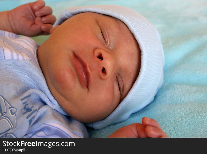 Week old baby boy on a blue blanket early in the morning. Week old baby boy on a blue blanket early in the morning