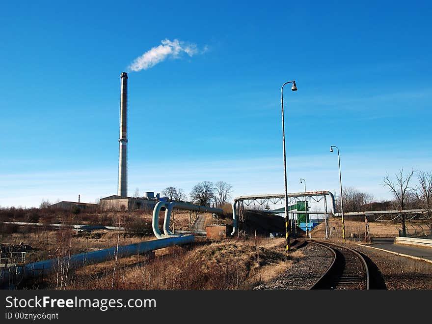 Industrial plant with pipes leading to chimney and railroad