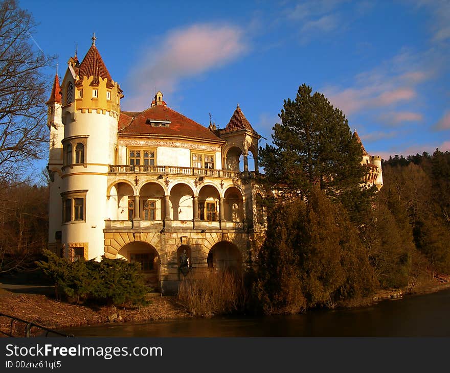 Beautiful romantic castle with river and forest at sunset