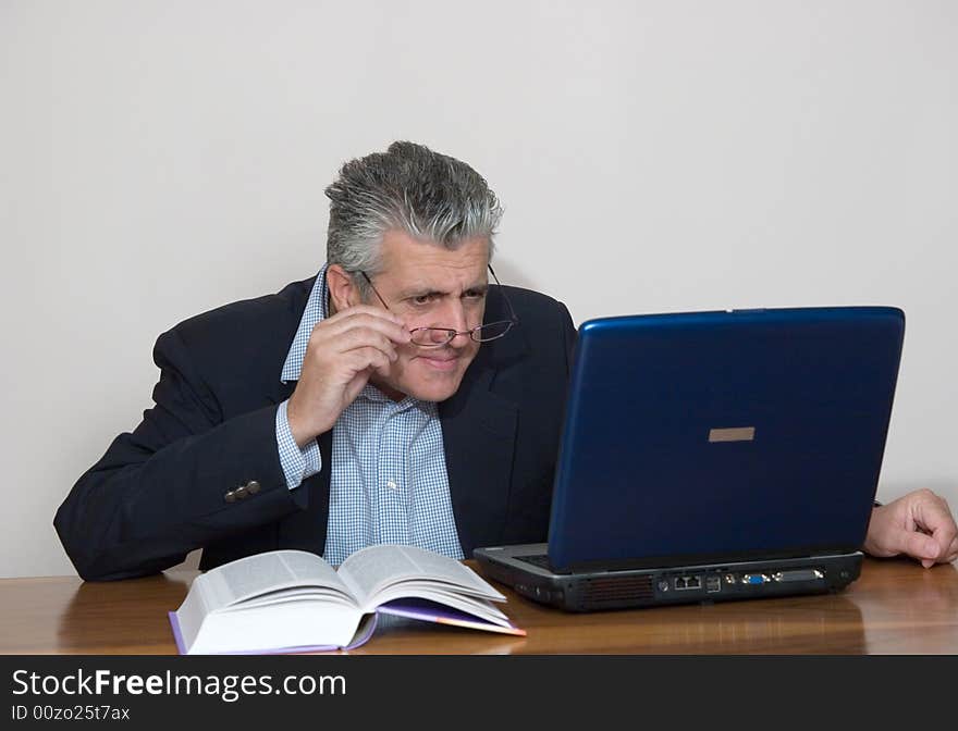 A businessman working in his study with a computer. A businessman working in his study with a computer