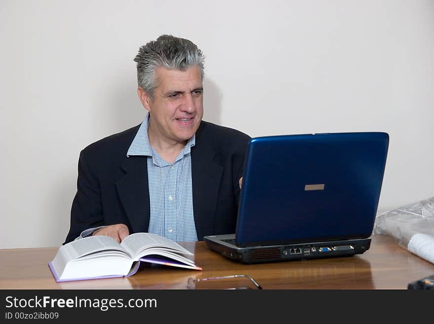 A businessman working in his study with a computer. A businessman working in his study with a computer