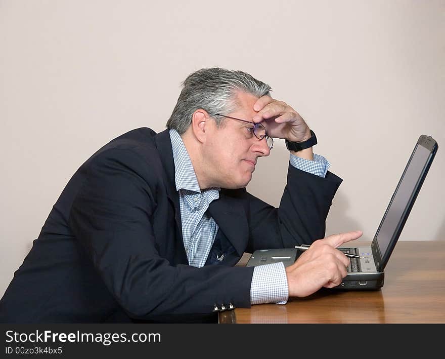 A businessman working in his study with a computer. A businessman working in his study with a computer