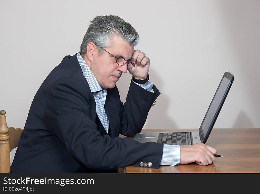 A businessman working in his study with a computer. A businessman working in his study with a computer