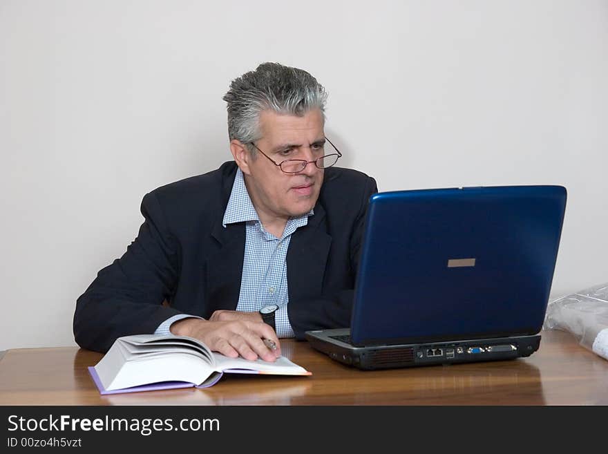 A businessman working in his study with a computer. A businessman working in his study with a computer