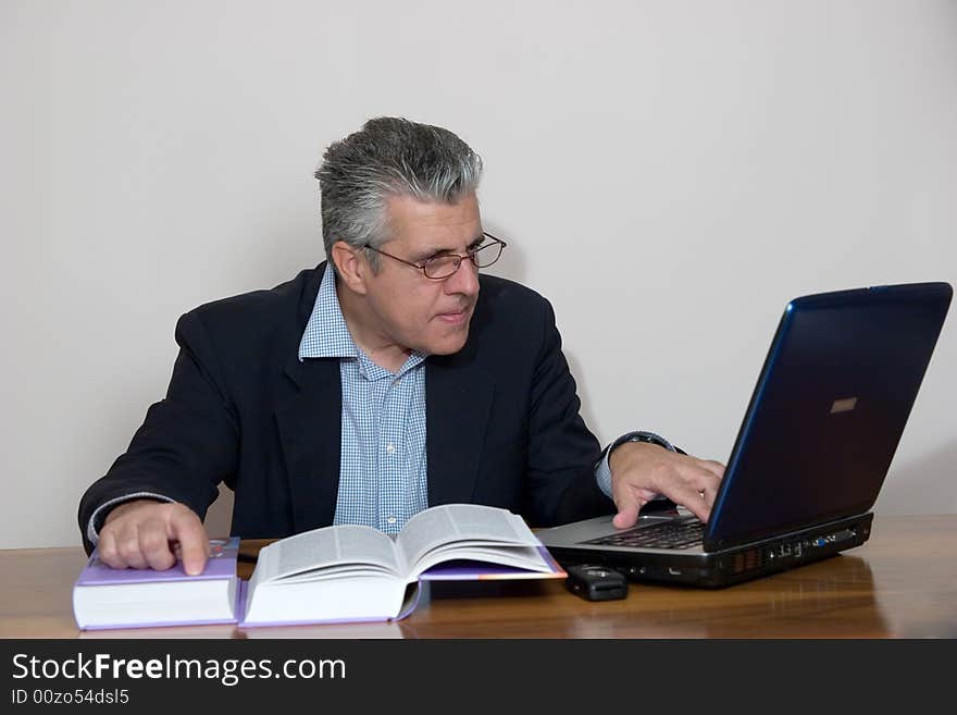 A businessman working in his study with a computer. A businessman working in his study with a computer