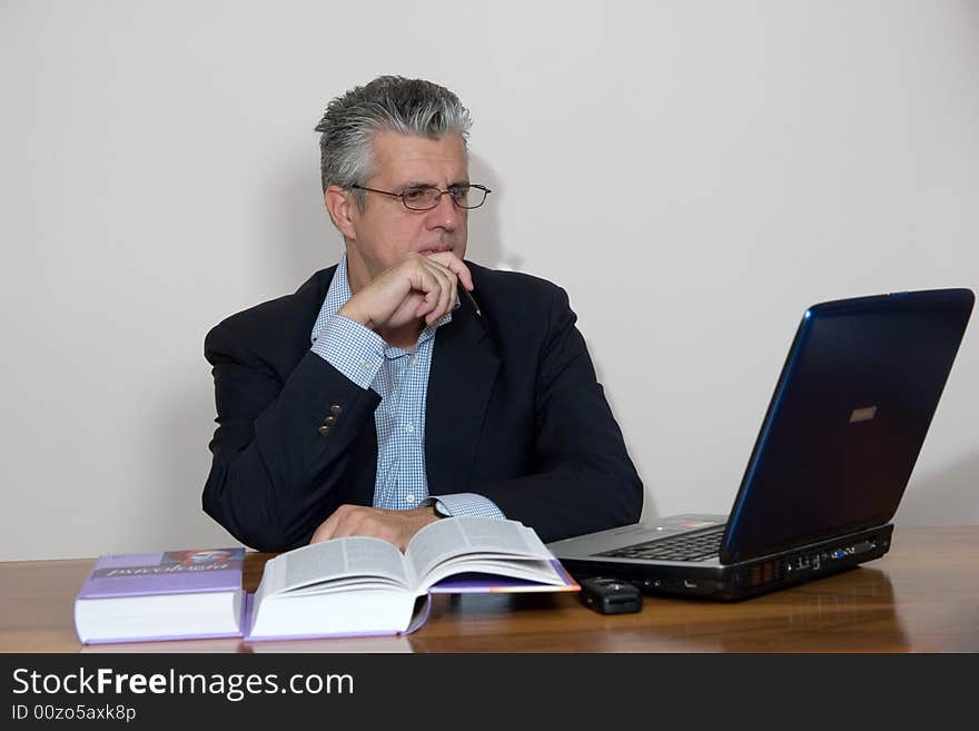 A businessman working in his study with a computer. A businessman working in his study with a computer