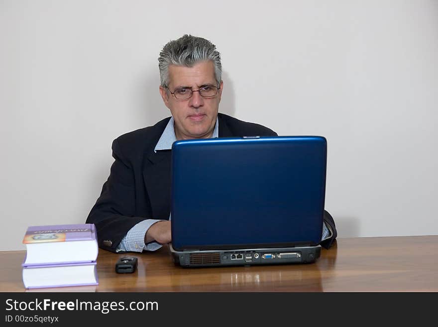 A businessman working in his study with a computer. A businessman working in his study with a computer