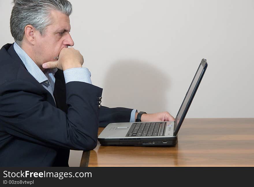 A businessman while writing a report in his study in a very concentrated way with a computer. A businessman while writing a report in his study in a very concentrated way with a computer