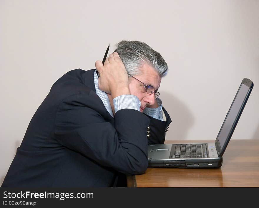 A businessman while writing a report in his study in a very concentrated way with a computer. A businessman while writing a report in his study in a very concentrated way with a computer