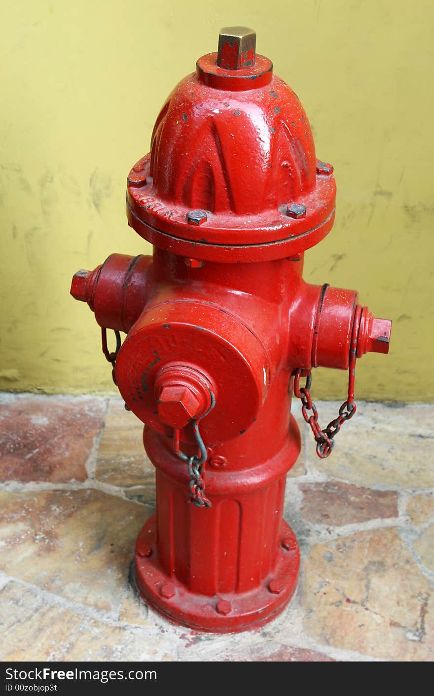 A bright red fire hyrant on a stone tiled sidewalk. A bright red fire hyrant on a stone tiled sidewalk