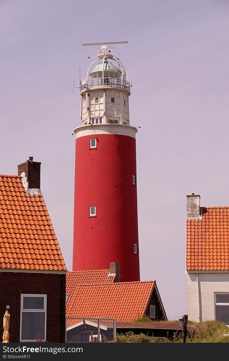 A red lighthouse and houses in the dunes of an isle