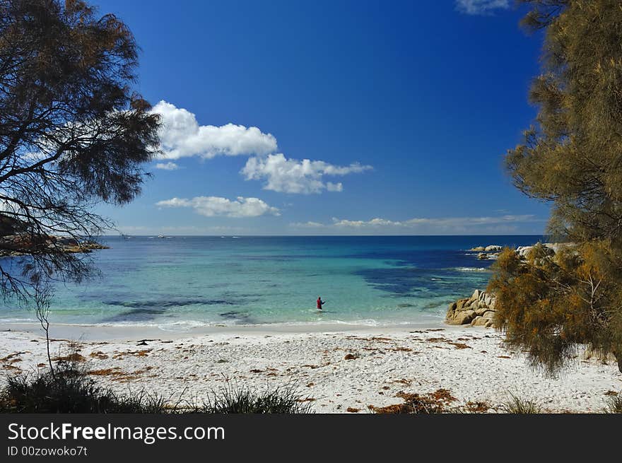 A lone fisherman, standing waist-deep in water, casts his line into a tropical bay. Space for copy in the sky. A lone fisherman, standing waist-deep in water, casts his line into a tropical bay. Space for copy in the sky.