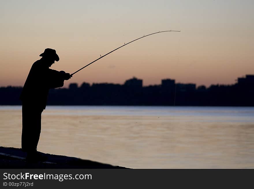 Siluett of the fisherman near the river when the Sun goes down. Siluett of the fisherman near the river when the Sun goes down