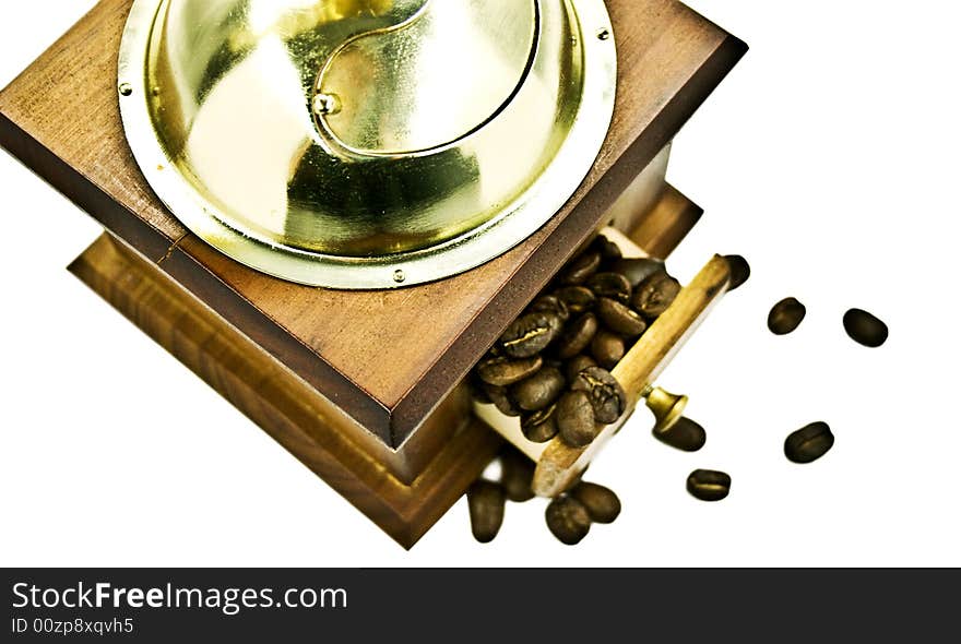 Wooden coffee grinder with coffee grains on a white background