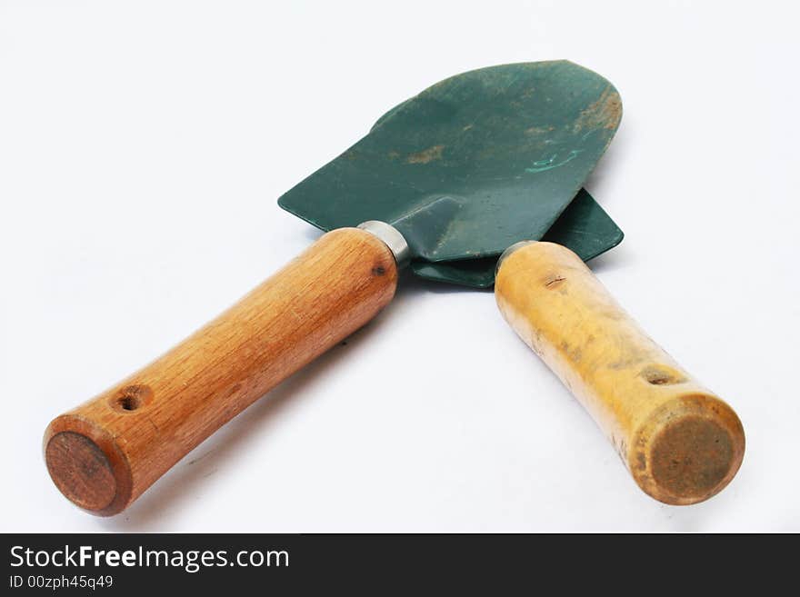 Two garden hand shovels crossed on white background with shallow depth of field. Two garden hand shovels crossed on white background with shallow depth of field