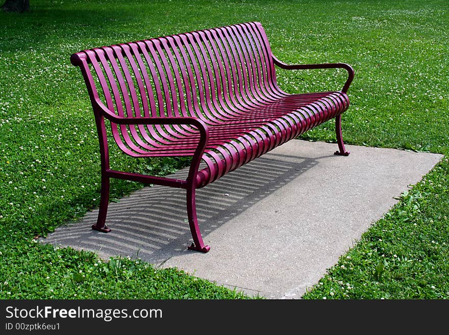 A red bench sits empty and waiting in a park. A red bench sits empty and waiting in a park.