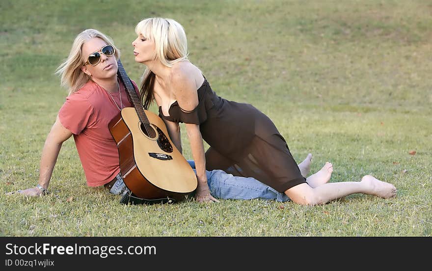 Hip adult couple with a guitar outside on grass. Hip adult couple with a guitar outside on grass