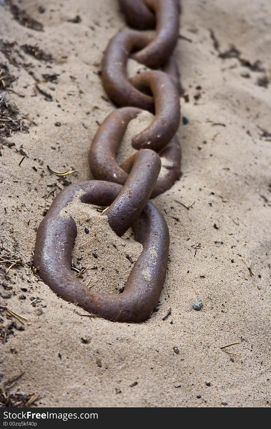 Old rusty chain close up laying on the beach