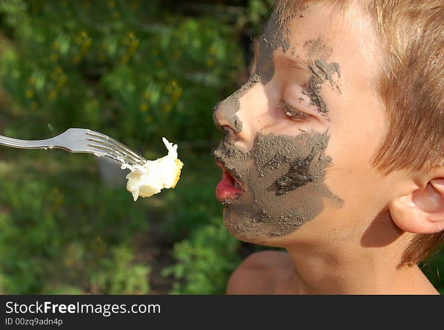 Muddy faced boy having a fast snack with the help of his mother while the short break in the game. Muddy faced boy having a fast snack with the help of his mother while the short break in the game