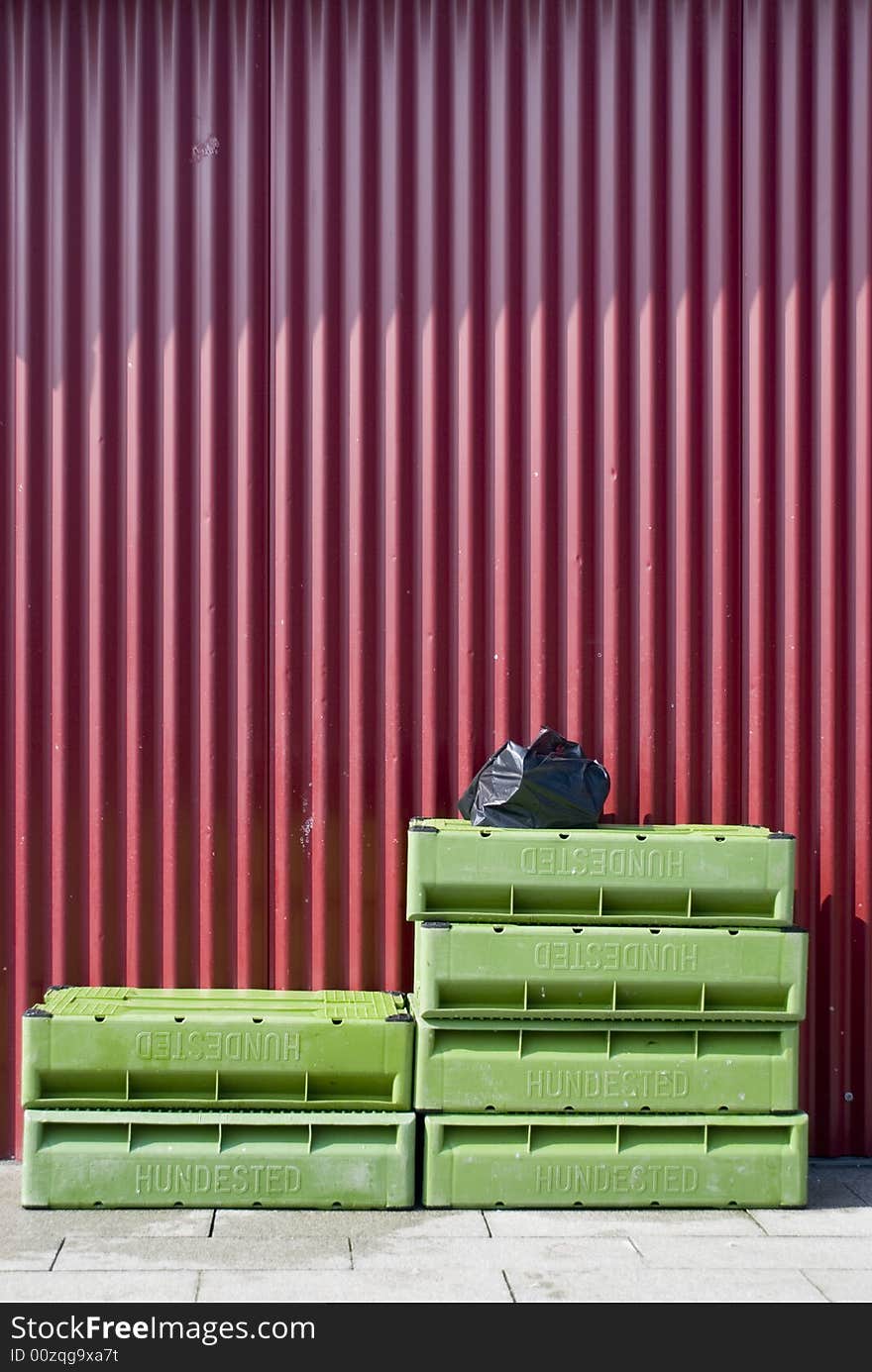 Some green fish boxes at a red wall