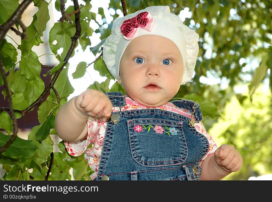 Little girl and green trees branchlets.