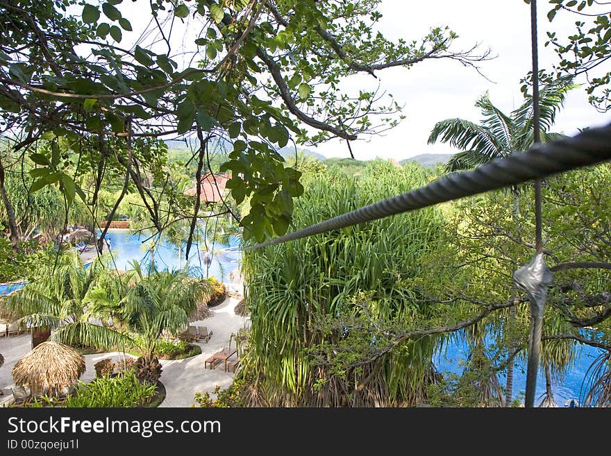 A zip line over a tropical resort swimming pool. A zip line over a tropical resort swimming pool