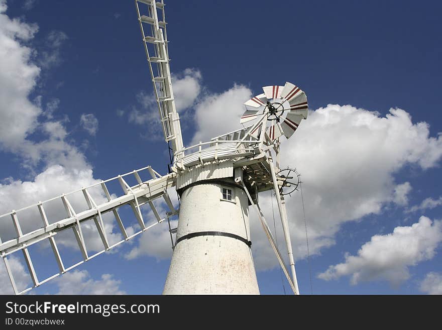 Dramtic view of white windmill set against blue sky with clouds