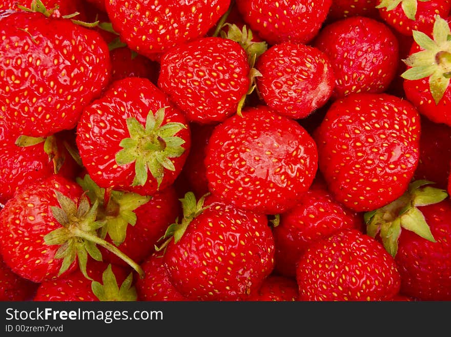 Red fresh strawberries with green leaves background