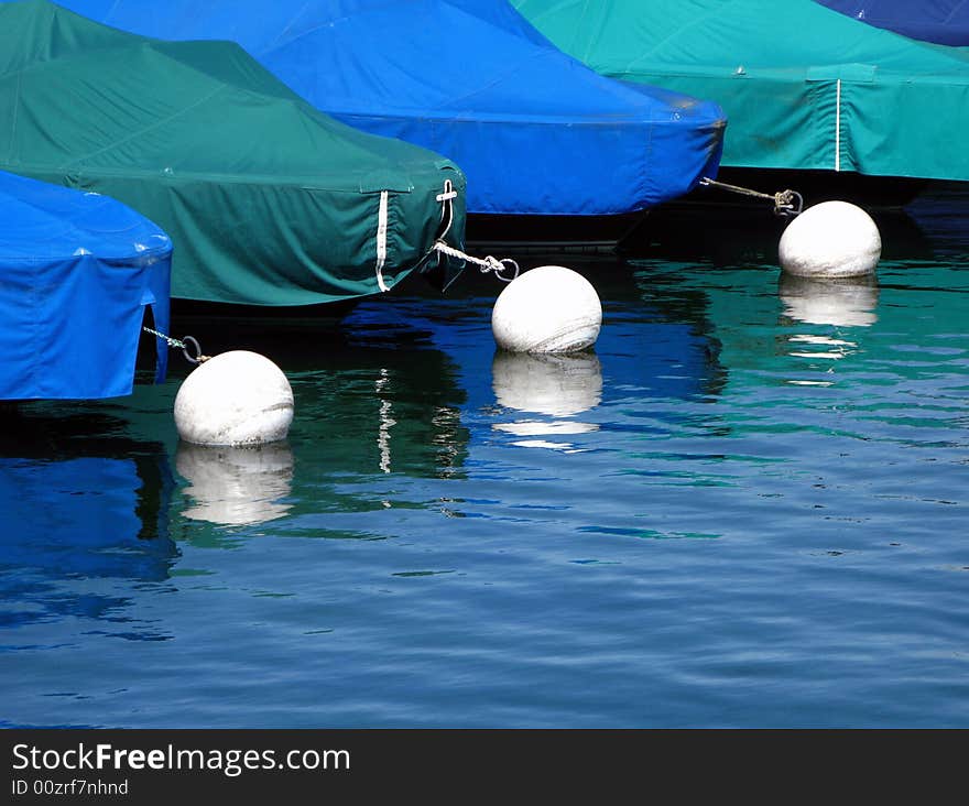 Abstract of boats docked in the port of Geneva, Switzerland with assorted covers of different nuances of blue and green reflecting in the calm waters of the enclosed marina. Abstract of boats docked in the port of Geneva, Switzerland with assorted covers of different nuances of blue and green reflecting in the calm waters of the enclosed marina.