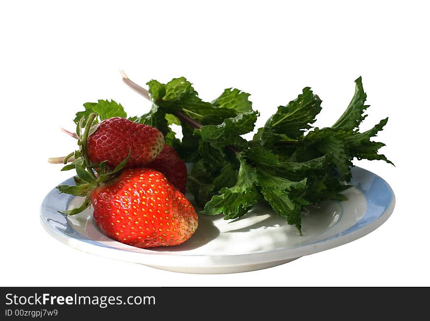 On a plate with the blue border shined with beams of the sun, the strawberry and mint leaves lies