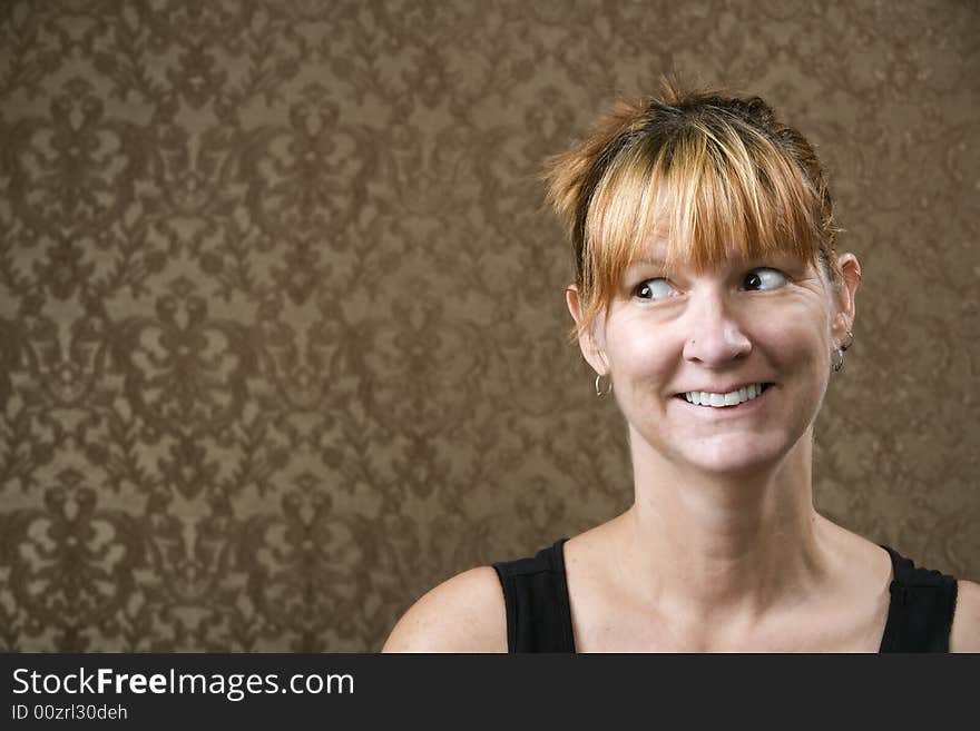 Pretty woman smiling in front of a gold-flocked wallpaper background