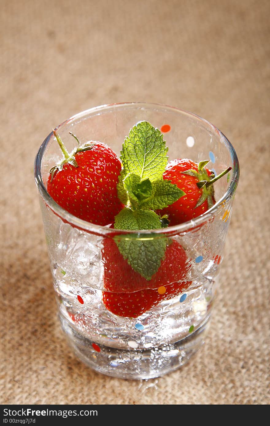 Strawberry, mint, ice cubes and water in wet glass