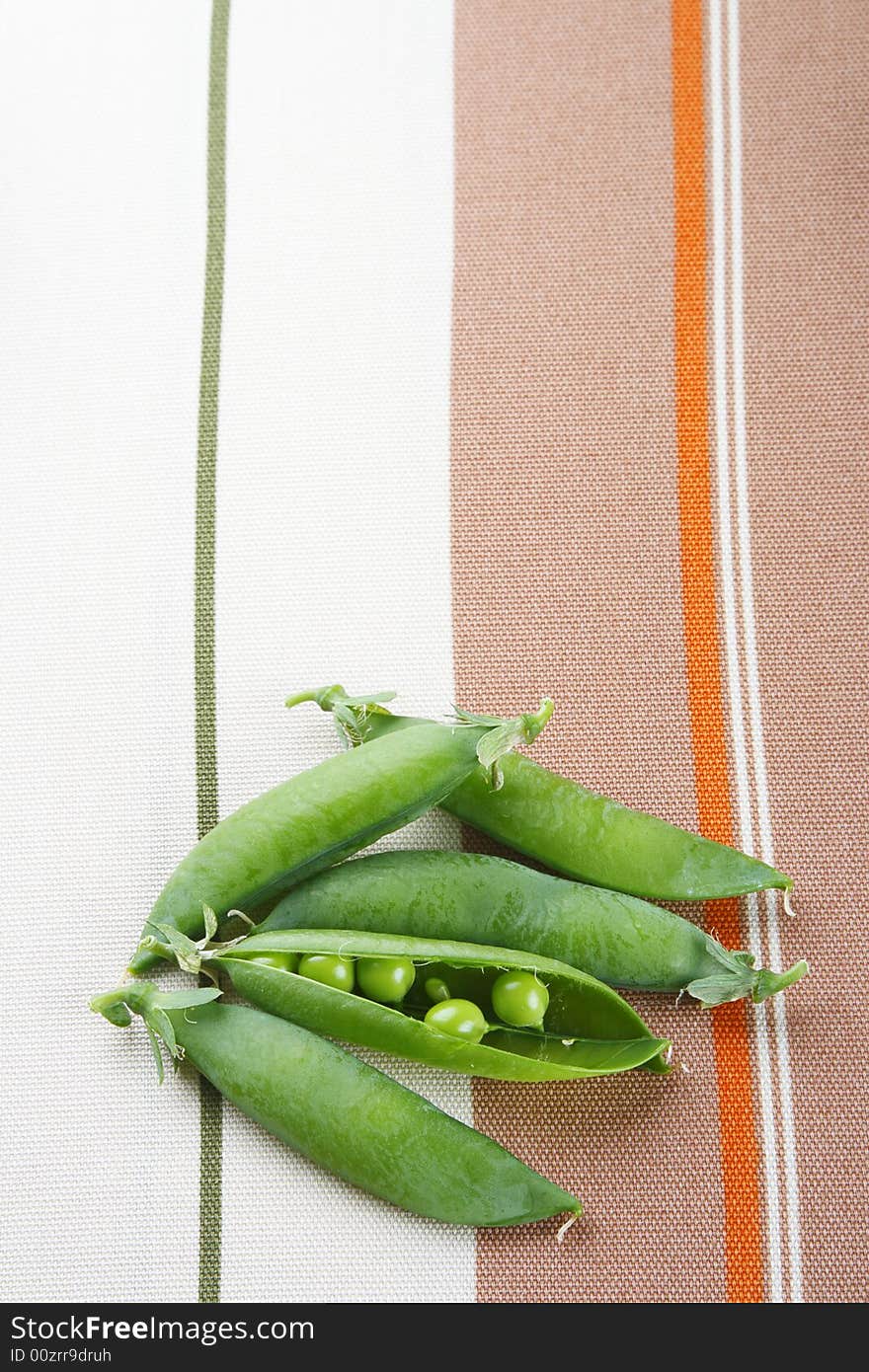 Fresh green peas on tablecloth background