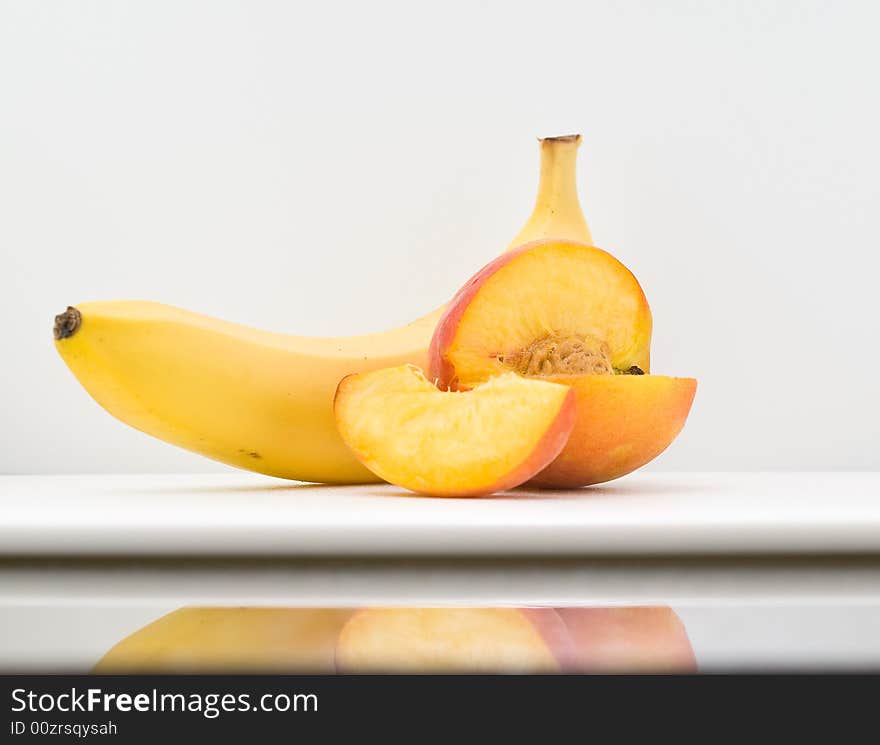 A sliced peach and ripe banana on white background. A sliced peach and ripe banana on white background.