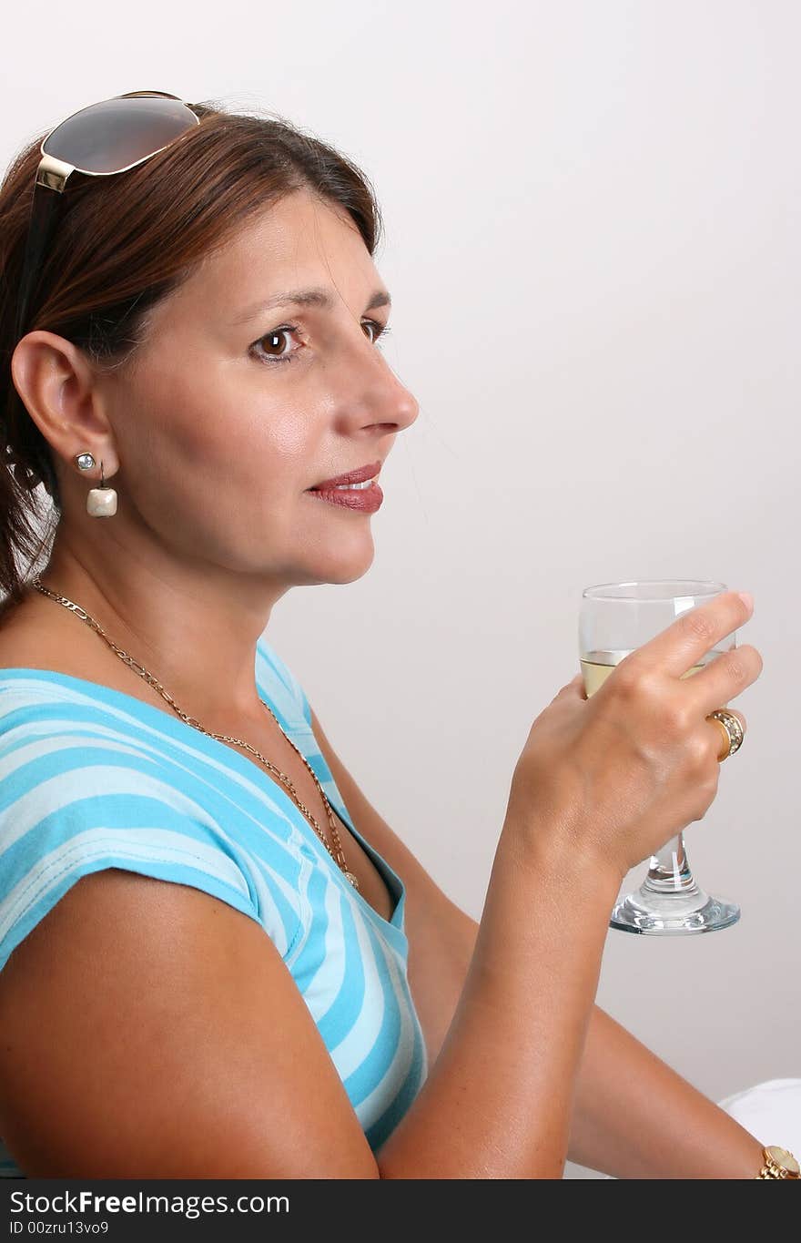 Adult Female Model wearing a blue top with a glass of wine. Adult Female Model wearing a blue top with a glass of wine