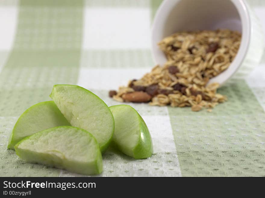 A sliced green apple with a bowl of muesli. A sliced green apple with a bowl of muesli.