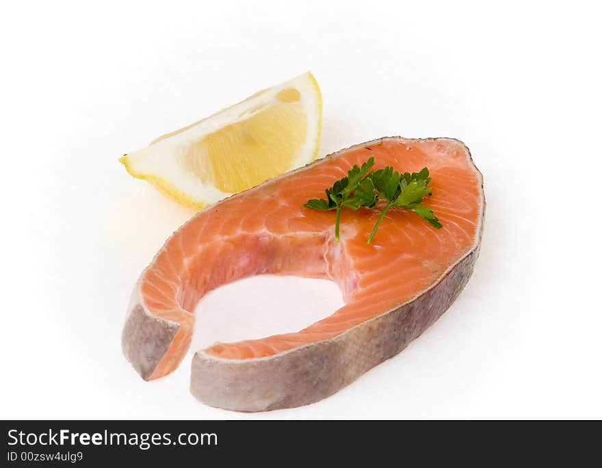 Salmon steak with lemon segment on white ground